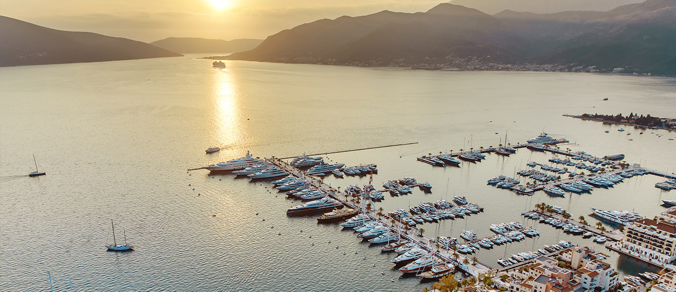 Aerial view of a marina at sunset with mountains in the background